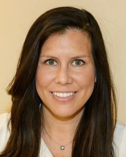 Professional headshot of a woman smiling at camera in dental office setting.