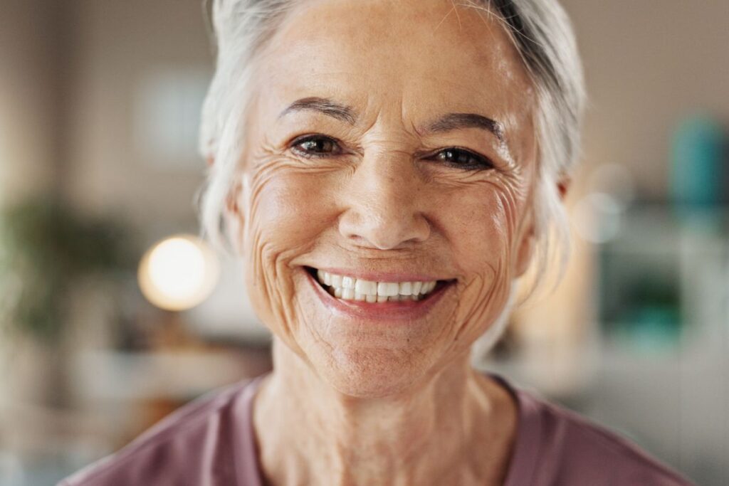 A smiling older woman shows a confident expression, highlighting healthy teeth and facial appearance in later years.
