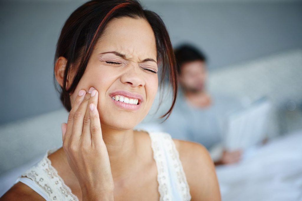 Woman experiencing tooth and jaw pain that may indicate a dental implant complication in Maitland, FL